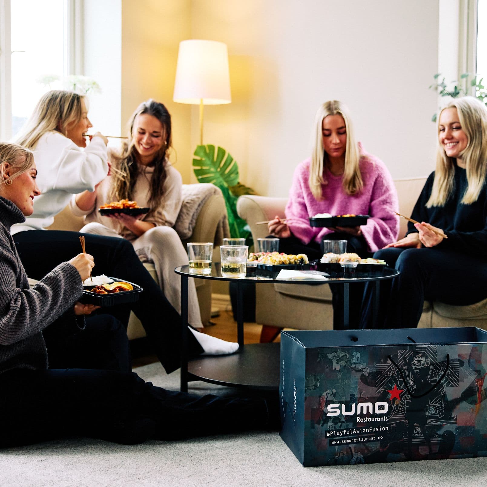 Friends sharing Sumo takeout on a sofa